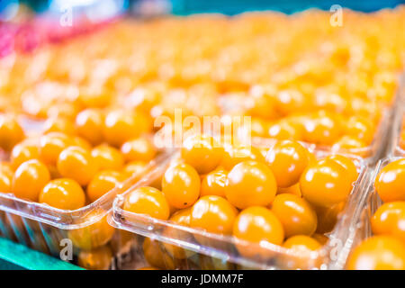 Macro closeup di colore giallo brillante pomodori ciliegia in scatole di plastica sul display Foto Stock