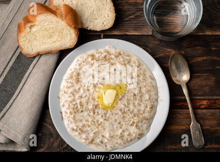 Vista superiore della atmeal porridge nel recipiente scuro su uno sfondo di legno Foto Stock