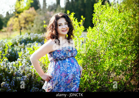 Outdoor Ritratto di giovane donna in stato di gravidanza nel campo. bella donna incinta nella corona rilassarsi in estate la natura prato. donna incinta relaxina Foto Stock