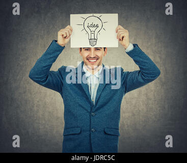 Imprenditore sorridente o docente in possesso di un libro bianco sopra la sua testa con una lampadina sketch. Scienza e business idea concetto isolato su backg grigio Foto Stock