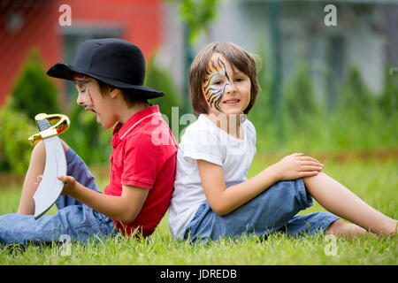 Due figli, fratelli, dipinta come tiger e pirata, giocare insieme in giardino, divertirsi, primavera Foto Stock