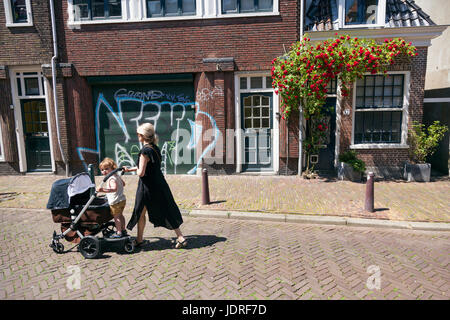 Leeuwarden, Paesi Bassi, 11 giugno 2017: la madre e il bambino ragazza con carrello pass house con Rose in leeuwarden su soleggiate giornate estive Foto Stock