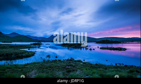 I riflessi della tarda sera Cielo in piena estate nel piccolo lochan su Rannoch Moor, vicino a Glencoe nelle Highlands scozzesi Foto Stock