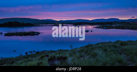 I riflessi della tarda sera Cielo in piena estate nel piccolo lochan su Rannoch Moor, vicino a Glencoe nelle Highlands scozzesi Foto Stock