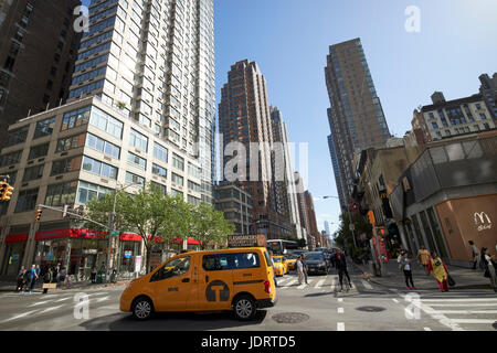Guardando verso il basso lungo la 6th avenue tra Chelsea (destra) e nomad (sinistra) con taxi giallo attraversando la città di New York STATI UNITI D'AMERICA Foto Stock