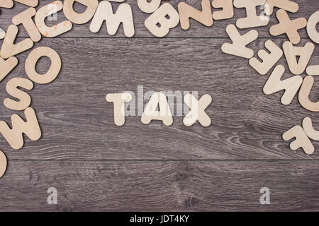 Tassa di parola fatta con lettere di legno accanto a un mucchio di altre lettere sopra la tavola di legno di composizione superficiale Foto Stock