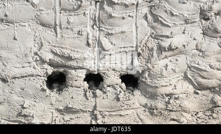Lo sfondo di cemento sulla parete liscio grigio testurizzato con cricche . grande figura e tre fori . Foto Stock