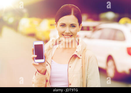 Donna sorridente che mostra smartphone tramite taxi in città Foto Stock