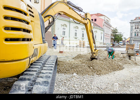 Piccolo escavatore è terreno di scavo presso il sito di costruzione, il progetto in corso. Foto Stock