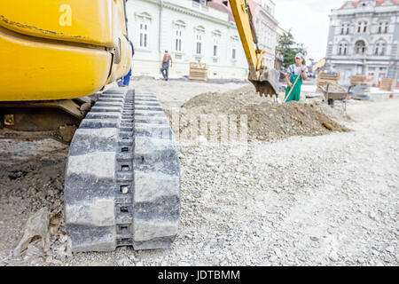 Piccolo escavatore è terreno di scavo presso il sito di costruzione, il progetto in corso. Foto Stock