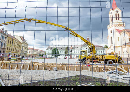 Vista sulla pompa gru per il sollevamento e la colata di cemento in cantiere mediante un filo di recinzione con forma quadratica. Foto Stock