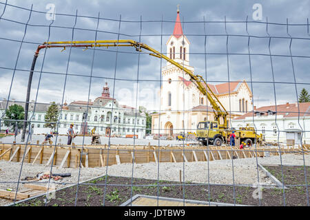 Vista sulla pompa gru per il sollevamento e la colata di cemento in cantiere mediante un filo di recinzione con forma quadratica. Foto Stock