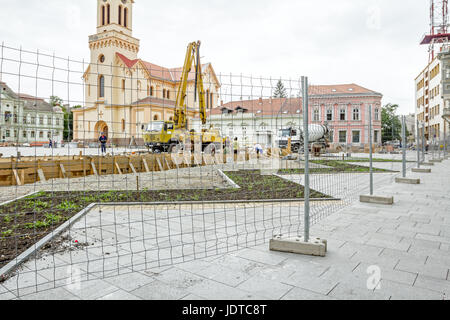 Vista sulla pompa gru per il sollevamento e la colata di cemento in cantiere mediante un filo di recinzione con forma quadratica. Foto Stock