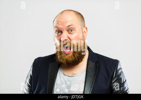 Urlando brutale uomo con barba di svuotare lo sfondo grigio Foto Stock