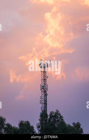 Torre di telecomunicazione con le antenne con il cielo al tramonto in background Foto Stock