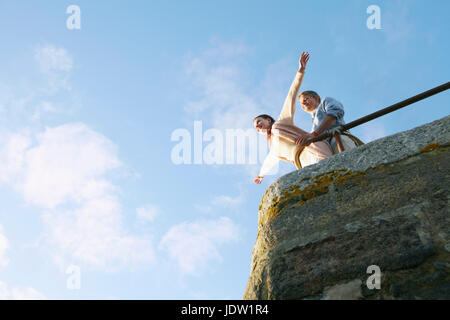 Giovane giocando sul bordo della parete di pietra Foto Stock