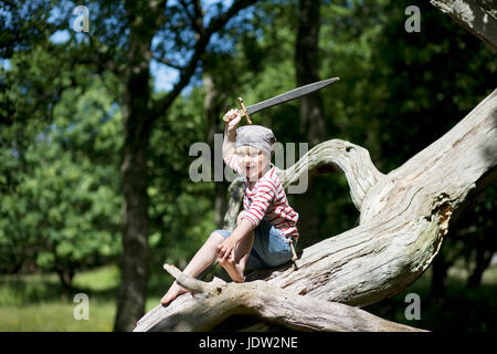 Ragazzo in costume pirata giocando su albero Foto Stock