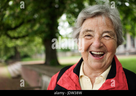 Donna anziana ridere in posizione di parcheggio Foto Stock