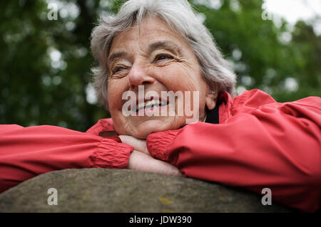 Donna anziana poggiante sulla roccia in posizione di parcheggio Foto Stock