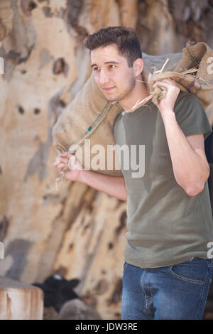 Giovane uomo che porta sacco pesante Foto Stock