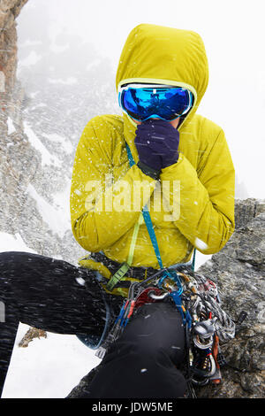 Metà donna adulta indossando giacca gialla e maschere da sci nella neve Foto Stock