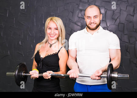 Sport, bodybuilding, lo stile di vita e il concetto di popolo sorridente - uomo e donna con barbell Foto Stock