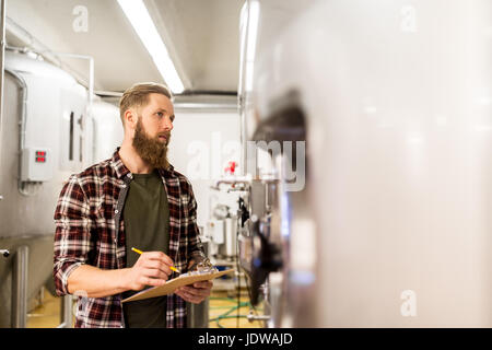 Uomo con appunti alla birreria artigianale o impianto di birra Foto Stock