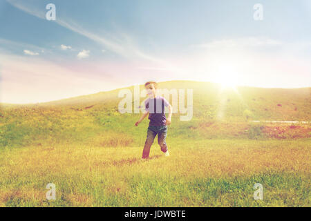 Happy little boy in esecuzione sul campo verde all'aperto Foto Stock