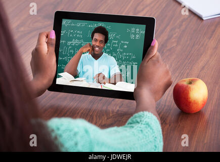 Immagine ritagliata di insegnante femmina assistenza degli studenti tramite videoconferenze in aula Foto Stock