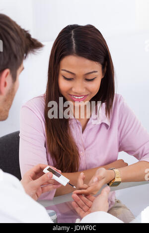 Immagine ritagliata maschile di medico di controllo del livello di glucosio nel paziente diabetico in cliniche Foto Stock