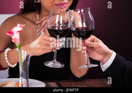 Immagine ritagliata della giovane tostare wineglasses nel ristorante Foto Stock