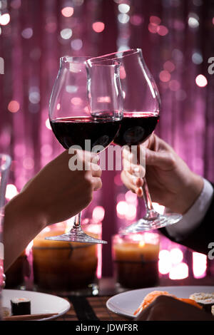 Immagine ritagliata della giovane tostare wineglasses nel ristorante Foto Stock