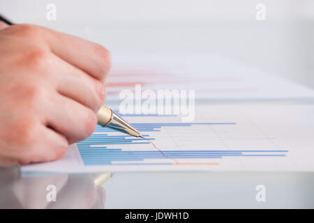 Immagine ritagliata di imprenditore analizzando il grafico alla scrivania in ufficio Foto Stock