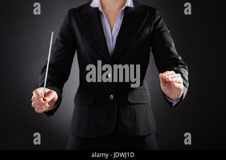 Close-up di femmine della Orchestra Holding Baton su sfondo nero Foto Stock