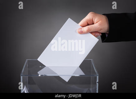 Close-up di mano mettendo in ballottaggio scatola di vetro Foto Stock