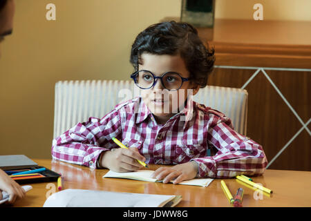 Ragazzo con grandi bicchieri arrotondati facendo i suoi compiti Foto Stock