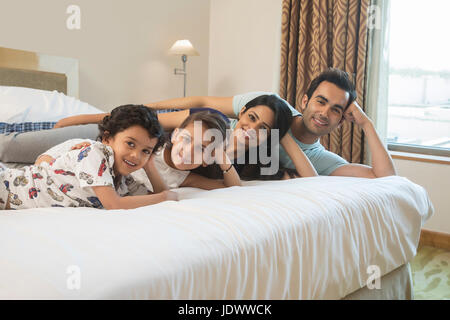 Ritratto di famiglia sorridente posa sul letto Foto Stock