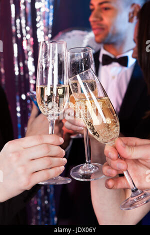 Immagine ritagliata di amici di tostatura flauti champagne al nightclub Foto Stock
