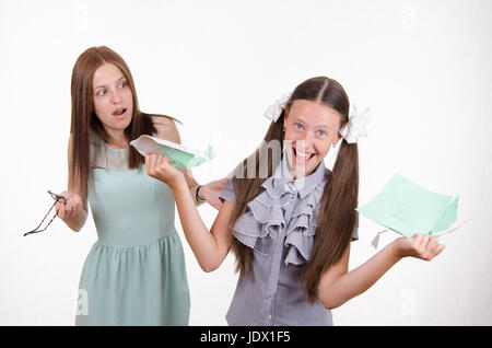 Schoolgirl divertendosi di strappare il notebook nella parte anteriore di un insegnante arrabbiato Foto Stock