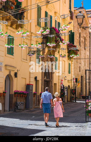 Coppia matura vacanza Mediterranea, una coppia di mezza età passeggiata attraverso la città vecchia di Alghero, Sardegna settentrionale, Italia. Foto Stock
