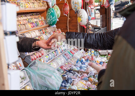 Il venditore accetta il pagamento dal turista per le sue merci nel mercato sulla città vecchia Sq. A Praga. Le colorate uova dipinte appartengono alla tradizionale Pasqua Foto Stock