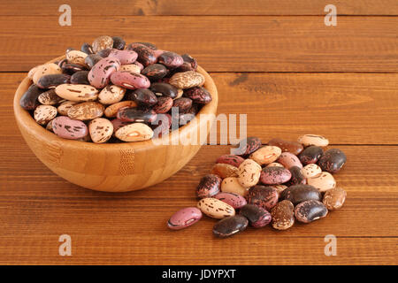 Materie viola, rosa, beige marrone con screziato fagioli kidney sul recipiente di legno marrone al tavolo di legno. Primo piano Foto Stock