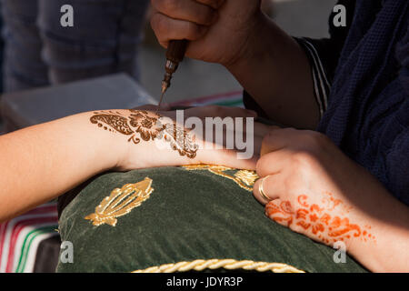 Dettaglio di immagine di henna essendo applicato a mano sul verde e oro cuscino in tessuto Foto Stock