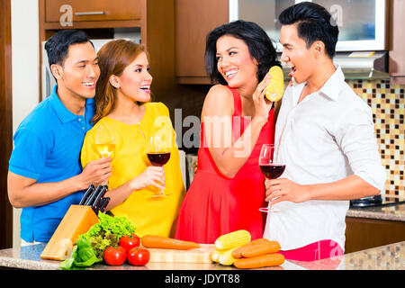 Amici asiatici come tagliare le verdure La cucina insieme in cucina domestica per cena, bere vino Foto Stock