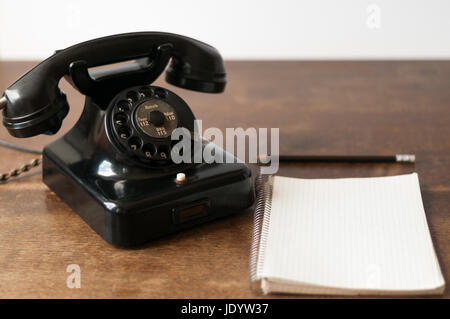 Altes Telefon mit Schreibblock fuer Textfreiraum und Bleistift auf einem Schreibtisch. Foto Stock