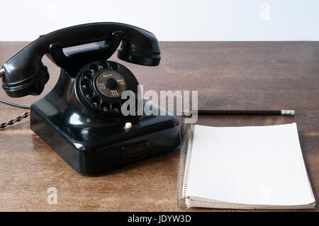 Altes Telefon mit Schreibblock fuer Textfreiraum und Bleistift auf einem Schreibtisch. Foto Stock