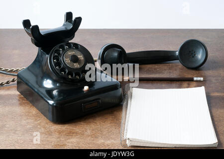 Altes Telefon mit Schreibblock fuer Textfreiraum und Bleistift auf einem Schreibtisch. Foto Stock