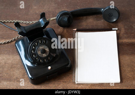 Altes Telefon mit Schreibblock fuer Textfreiraum und Bleistift auf einem Schreibtisch. Foto Stock