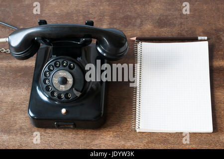 Altes Telefon mit Schreibblock fuer Textfreiraum und Bleistift auf einem Schreibtisch. Foto Stock