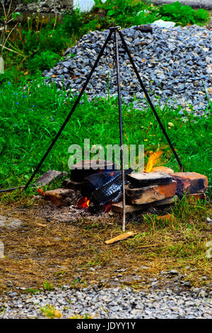 La cottura a fuoco in aria aperta, fuoco, stand su tre supporti sotto la pentola Foto Stock